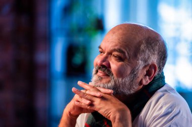 Hintli kıdemli bir adam derin düşüncelere dalmış parlak, modern bir evde koltukta otururken düşünceli, asyalı, yaşlı ve endişeli bir yüz ifadesi olan yaşlı bir adam kapalı alanda ciddi düşüncelere dalmış.