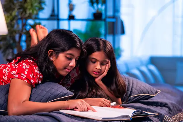 Hintli kardeş kardeşler kitap okurken birlikte sessiz zaman geçirmenin tadını çıkarıyorlar. Renkli kıyafetler giyen Asyalı küçük kızlar boş zamanlarında kapalı bir odada kitap okumaya odaklanırlar.