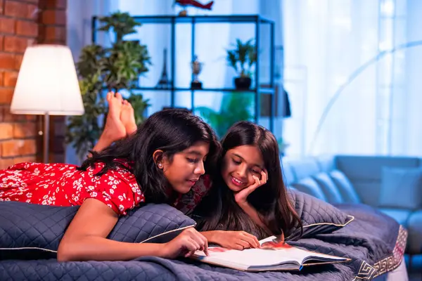 Hintli kardeş kardeşler kitap okurken birlikte sessiz zaman geçirmenin tadını çıkarıyorlar. Renkli kıyafetler giyen Asyalı küçük kızlar boş zamanlarında kapalı bir odada kitap okumaya odaklanırlar.