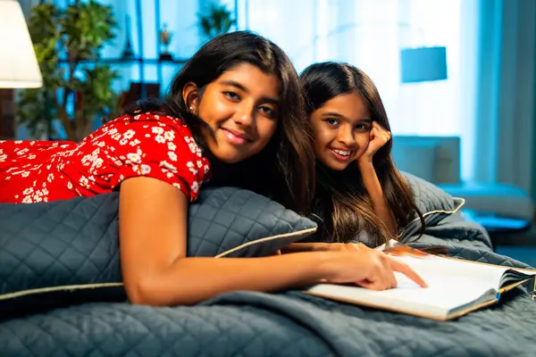 Hintli kardeş kardeşler kitap okurken birlikte sessiz zaman geçirmenin tadını çıkarıyorlar. Renkli kıyafetler giyen Asyalı küçük kızlar boş zamanlarında kapalı bir odada kitap okumaya odaklanırlar.