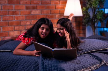 Hintli kardeş kardeşler kitap okurken birlikte sessiz zaman geçirmenin tadını çıkarıyorlar. Renkli kıyafetler giyen Asyalı küçük kızlar boş zamanlarında kapalı bir odada kitap okumaya odaklanırlar.