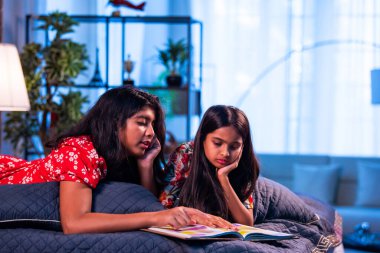 Hintli kardeş kardeşler kitap okurken birlikte sessiz zaman geçirmenin tadını çıkarıyorlar. Renkli kıyafetler giyen Asyalı küçük kızlar boş zamanlarında kapalı bir odada kitap okumaya odaklanırlar.