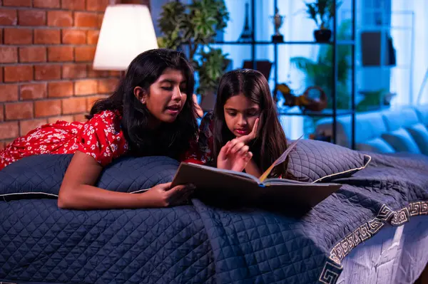 Hintli kardeş kardeşler kitap okurken birlikte sessiz zaman geçirmenin tadını çıkarıyorlar. Renkli kıyafetler giyen Asyalı küçük kızlar boş zamanlarında kapalı bir odada kitap okumaya odaklanırlar.