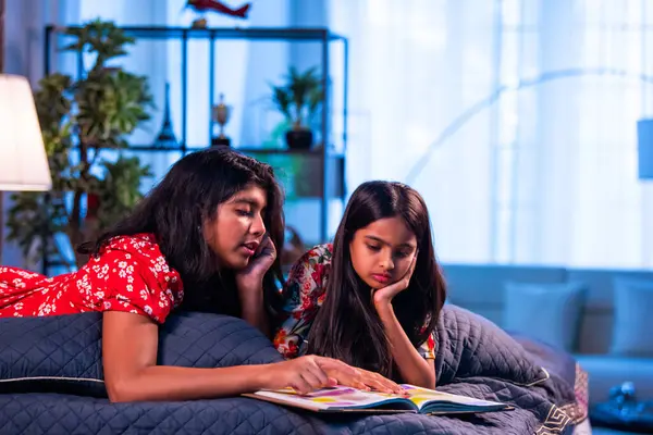 Hintli kardeş kardeşler kitap okurken birlikte sessiz zaman geçirmenin tadını çıkarıyorlar. Renkli kıyafetler giyen Asyalı küçük kızlar boş zamanlarında kapalı bir odada kitap okumaya odaklanırlar.