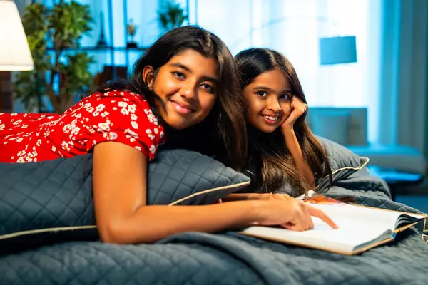 Hintli kardeş kardeşler kitap okurken birlikte sessiz zaman geçirmenin tadını çıkarıyorlar. Renkli kıyafetler giyen Asyalı küçük kızlar boş zamanlarında kapalı bir odada kitap okumaya odaklanırlar.