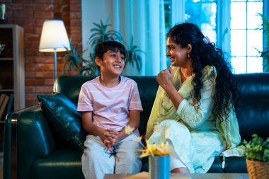 Hintli anne küçük çocuk kanepenin üzerinde modern evde sohbet ediyor, birlikte kaliteli zaman geçiriyorlar, sevgi, sevgi, sıcaklık, ilgi, mutluluk, ebeveyn-çocuk ilişkisi günlük rutin yaşam tarzı.