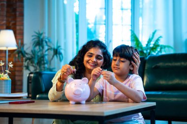 Hintli anne oğul, modern evdeki domuz kumbarasına bozuk para koyuyor, küçük yaşta para biriktirmeyi öğretiyor, kaliteli bağ kurma zamanını paylaşıyor, ebeveyn öğrenimi, şefkat, rehberlik...