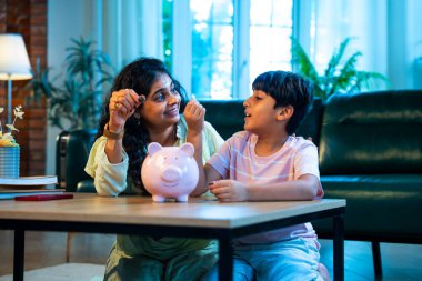 Hintli anne oğul, modern evdeki domuz kumbarasına bozuk para koyuyor, küçük yaşta para biriktirmeyi öğretiyor, kaliteli bağ kurma zamanını paylaşıyor, ebeveyn öğrenimi, şefkat, rehberlik...