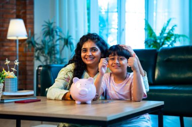 Hintli anne oğul, modern evdeki domuz kumbarasına bozuk para koyuyor, küçük yaşta para biriktirmeyi öğretiyor, kaliteli bağ kurma zamanını paylaşıyor, ebeveyn öğrenimi, şefkat, rehberlik...