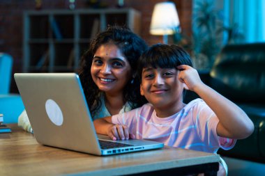 Hintli evlat dizüstü bilgisayar kullanmayı öğrenirken, anne merakla modern evde izliyor, birlikte kaliteli zaman geçiriyorlar, teknolojiyi keşfediyorlar, neşeyi paylaşıyorlar, ebeveyn bağı kuruyorlar, öğrenmeyi büyütüyorlar.