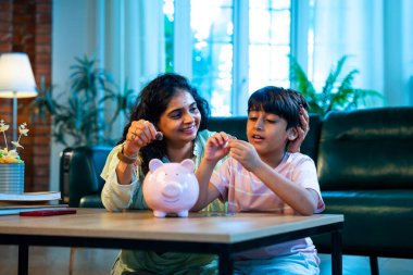 Hintli anne oğul, modern evdeki domuz kumbarasına bozuk para koyuyor, küçük yaşta para biriktirmeyi öğretiyor, kaliteli bağ kurma zamanını paylaşıyor, ebeveyn öğrenimi, şefkat, rehberlik...