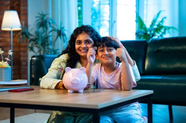 Hintli anne oğul, modern evdeki domuz kumbarasına bozuk para koyuyor, küçük yaşta para biriktirmeyi öğretiyor, kaliteli bağ kurma zamanını paylaşıyor, ebeveyn öğrenimi, şefkat, rehberlik...