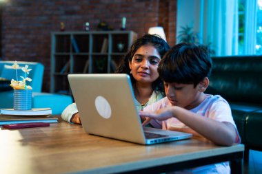 Hintli evlat dizüstü bilgisayar kullanmayı öğrenirken, anne merakla modern evde izliyor, birlikte kaliteli zaman geçiriyorlar, teknolojiyi keşfediyorlar, neşeyi paylaşıyorlar, ebeveyn bağı kuruyorlar, öğrenmeyi büyütüyorlar.