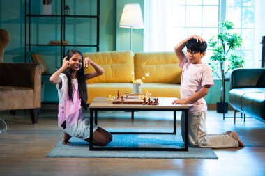 Evde satranç oynayan Hintli küçük kardeş, oturma odasında eğlenen küçük kardeşler, Asyalı çocuklar bağlanıyor, aile sevgisi, eğlenceli öğrenme, strateji