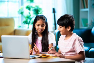 Hintli küçük kardeş evde dizüstü bilgisayarla ders çalışıyor, evde not defteri var, Asyalı küçük çocuklar birlikte öğreniyorlar modern oturma odasında bilgisayar teknolojisi, eğitim ve ev ödevi kullanıyorlar.