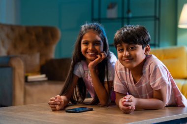 Hintli küçük kardeş akıllı telefon cihazlarıyla oyun oynuyor. Evde boş zaman geçiriyor. Asyalı küçük çocuklar çocukluk aktivitelerinin keyfini çıkarıyorlar.