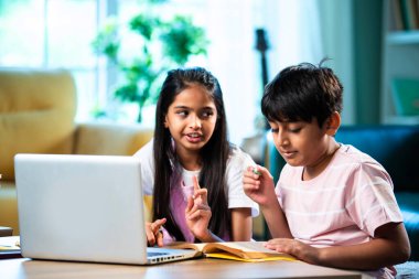 Hintli küçük kardeş evde dizüstü bilgisayarla ders çalışıyor, evde not defteri var, Asyalı küçük çocuklar birlikte öğreniyorlar modern oturma odasında bilgisayar teknolojisi, eğitim ve ev ödevi kullanıyorlar.