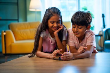 Hintli küçük kardeş akıllı telefon cihazlarıyla oyun oynuyor. Evde boş zaman geçiriyor. Asyalı küçük çocuklar çocukluk aktivitelerinin keyfini çıkarıyorlar.