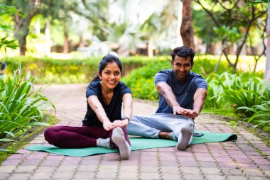 Hintli güzel genç çift yoga minderi üzerinde yoga yaparken huzurlu bir sabah seansında esneklik, sağIık, denge ve bütünsel sağlıklı yaşam tarzına odaklandılar.
