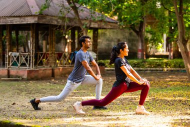Hintli güzel genç çift sabah antrenmanından sonra parkta egzersiz yaparken dinlenmenin, sağlıklı yaşam tarzının, temiz havanın ve yeşillikte kaynaşırken güneşin tadını çıkarıyorlar.