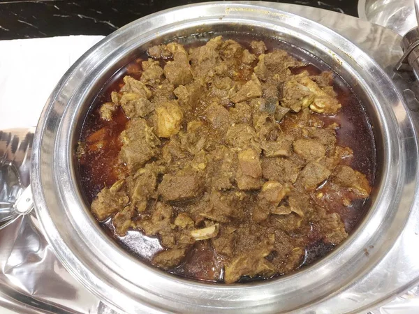 Büyük bir kasede koyun eti var. Keçi etinden hazırlanmış. Taşımak olarak da bilinir. Ana malzeme domates, soğan sarımsak, zencefil, genellikle pirinç ya da Hint ekmeğiyle servis edilir..