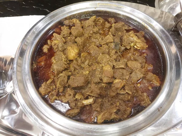 Büyük bir kasede koyun eti var. Keçi etinden hazırlanmış. Taşımak olarak da bilinir. Ana malzeme domates, soğan sarımsak, zencefil, genellikle pirinç ya da Hint ekmeğiyle servis edilir..