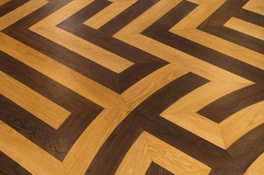 Ahşap zemin, zıt ışık ve karanlık panellerin geometrik desende sıralandığı ayrıntılı bir görünüm.