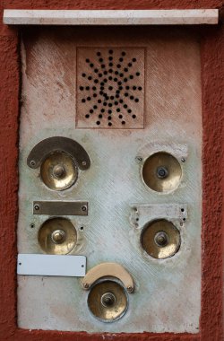 Duvar yüzeyinde çoklu bronz düğmeler bulunan klasik bir dahili iletişim paneli