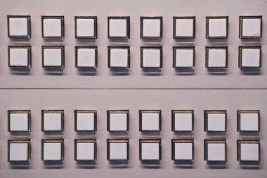 Temiz ve modern görünüm için bir kontrol paneli üzerinde simetrik satırlarda sıralanmış birden fazla beyaz düğmelerin yakın plan görüntüsü