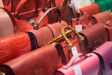 Renkli çantalardan oluşan canlı bir koleksiyon bir butik mağazasında güzelce düzenlenmiş.