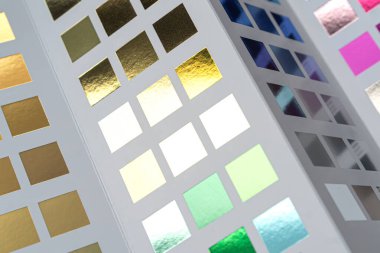 Tasarım ve baskı kataloğunda renkli metal folyo örnekleri, yaratıcı projelerde canlı renk paletleri ve malzemelerini seçme kavramı