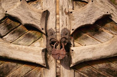 Yıpranmış dokusu ve antika demir kilidi olan taşra ahşap kapı, kırsal alanda güvenlik ve geleneği simgeliyor, gün ışığında ön manzara