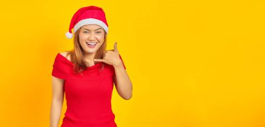 Çekici genç Asyalı kadın Noel şapkası takıyor. Çağrı işareti yap ve bana geri dön işareti ver.