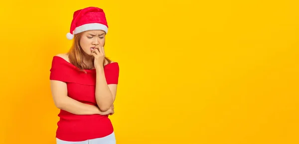 stock image Young Asian woman wearing Christmas hat looking stressed and nervous with hand on mouth biting nails