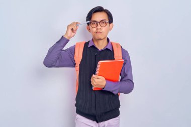 Sırt çantalı genç Asyalı öğrenciler ellerinde defterlerle gri arka planda izole edilmiş bir şeyi düşünüyorlar. Lise üniversite konsepti eğitimi