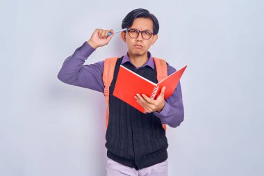 Sırt çantalı genç Asyalı öğrenciler ellerinde defterlerle gri arka planda izole edilmiş bir şeyi düşünüyorlar. Lise üniversite konsepti eğitimi