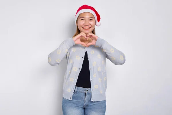 Atrakcyjna Młoda Azjatka Kapeluszu Świętego Mikołaja Pokazująca Gest Serca Obiema Zdjęcie Stockowe