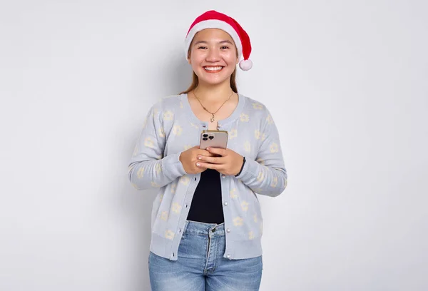 Wesoła Młoda Azjatka Kapeluszu Świątecznym Pomocą Telefonu Komórkowego Wpisując Sms Obrazek Stockowy