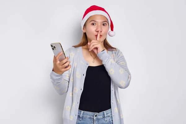 Poważna Młoda Azjatka Świątecznym Kapeluszu Trzymająca Telefon Komórkowy Wykonująca Gest Obraz Stockowy