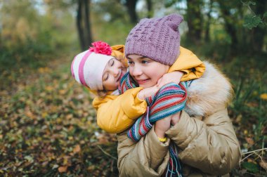 Küçük kız kardeş ablasına sarılıyor. Mutlu gülümseyen çocuklar sonbahar parkında eğleniyor..