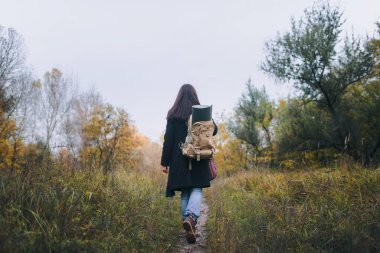 Genç kız turist kızın sırtında büyük bir sırt çantası içeren bir ormanda yürürken,.