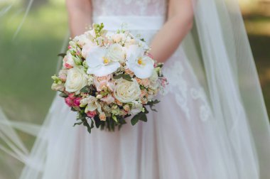 Beyaz elbiseli gelin elinde güzel bir düğün buketi tutuyor. Beyaz orkideler ve güller. Narin çiçekler..