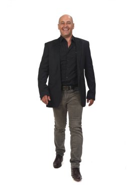 Ceketli, kot pantolonlu, yürüyen ve gülen bir adamın beyaz arka plandaki kameraya bakışı.,