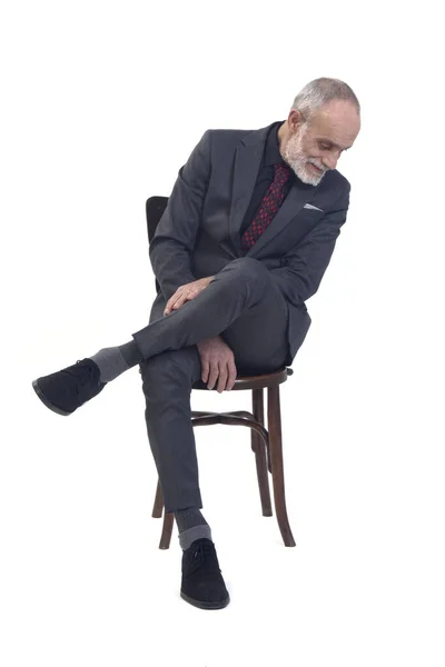 坐在椅子上 身穿西服 打着领带 双腿交叉 俯视白色背景的男人的前视图 — 图库照片