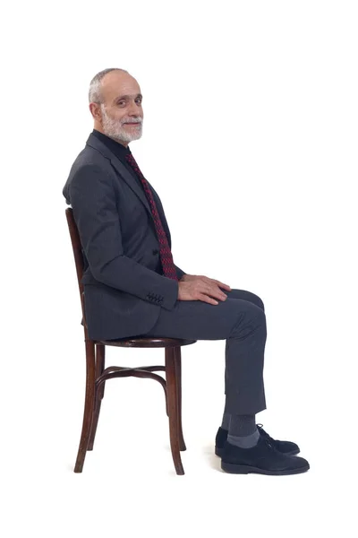 Widok Boku Człowieka Siedzącego Krześle Garniturze Krawacie Patrzącego Kamerę Białym — Zdjęcie stockowe