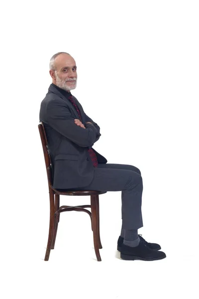 スーツとネクタイと腕を組んで椅子に座って白い背景のカメラを見ている男の側の景色 — ストック写真