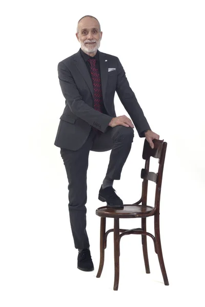 白い背景にカメラを見ながらスーツ姿の椅子で遊んでいる男の前の風景 — ストック写真