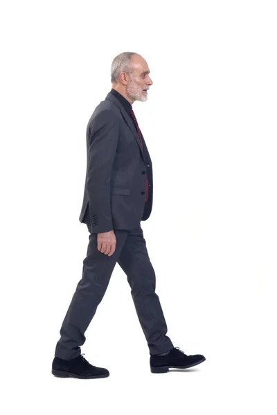 一个穿着西服打着领带在白色背景上行走的男人的侧视图 — 图库照片