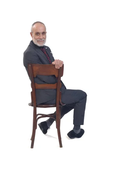 スーツを着た男が椅子に腰を下ろし白い背景のカメラを見て — ストック写真