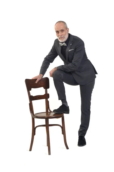 Mężczyzna Muszce Garniturze Bawi Się Krzesłem Patrzy Kamerę Białym Tle — Zdjęcie stockowe